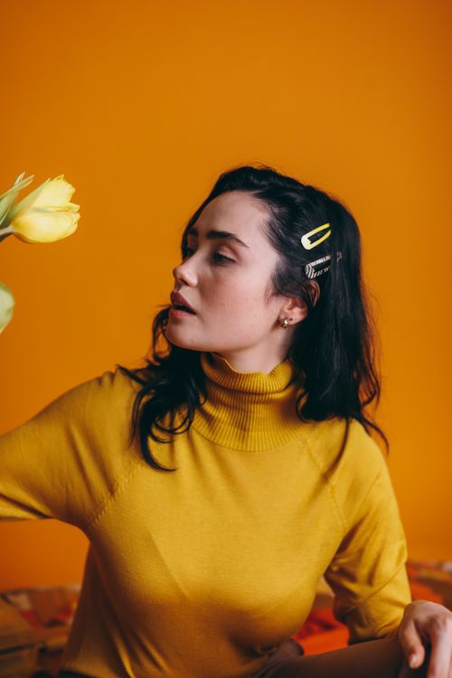Free Artistic portrait of a stylish woman in yellow with tulips against a matching background. Stock Photo