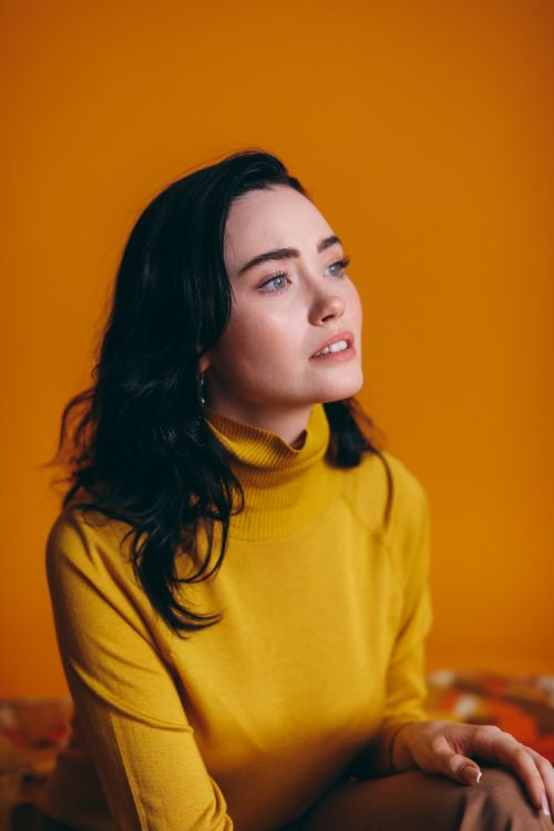 Free Elegant portrait of woman in yellow sweater against vibrant background. Stock Photo