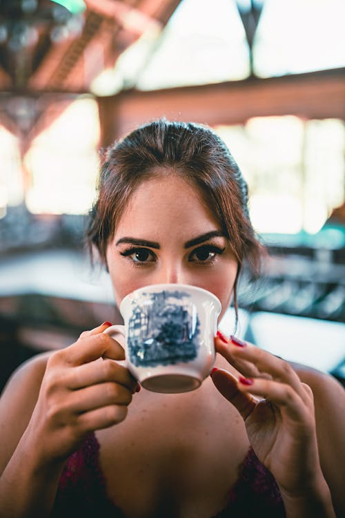 Content young female drinking tasty organic mug of coffee on blurred background in daytime