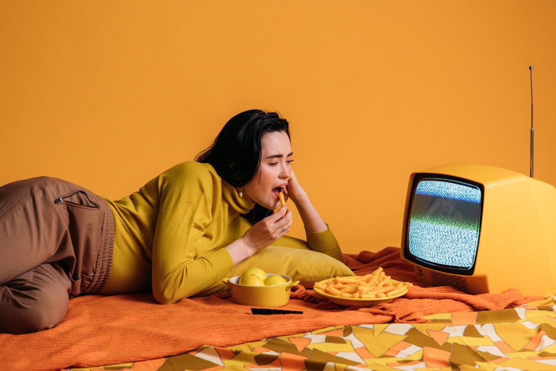 Free Woman in Yellow Long Sleeve Shirt Watching TV And Eatinghi Stock Photo