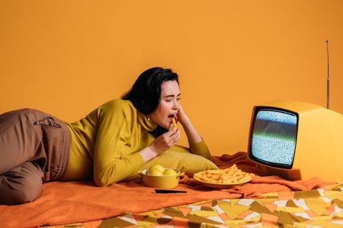 Free Woman in Yellow Long Sleeve Shirt Watching TV And Eatinghi Stock Photo