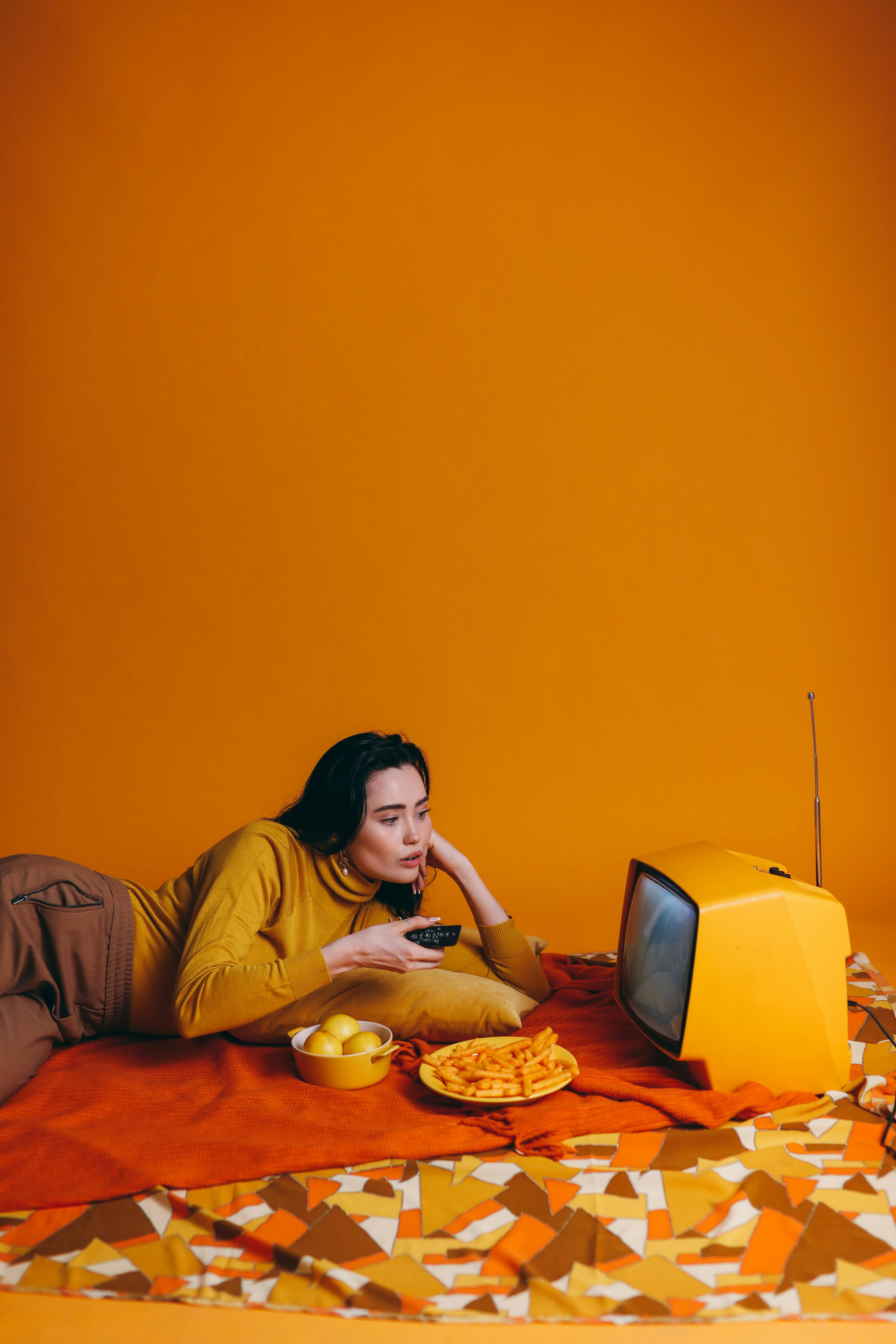 woman in yellow long sleeve shirt watching tv