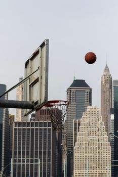 Basketball hoop and ball framed by a classic city skyline, depicting urban sports.