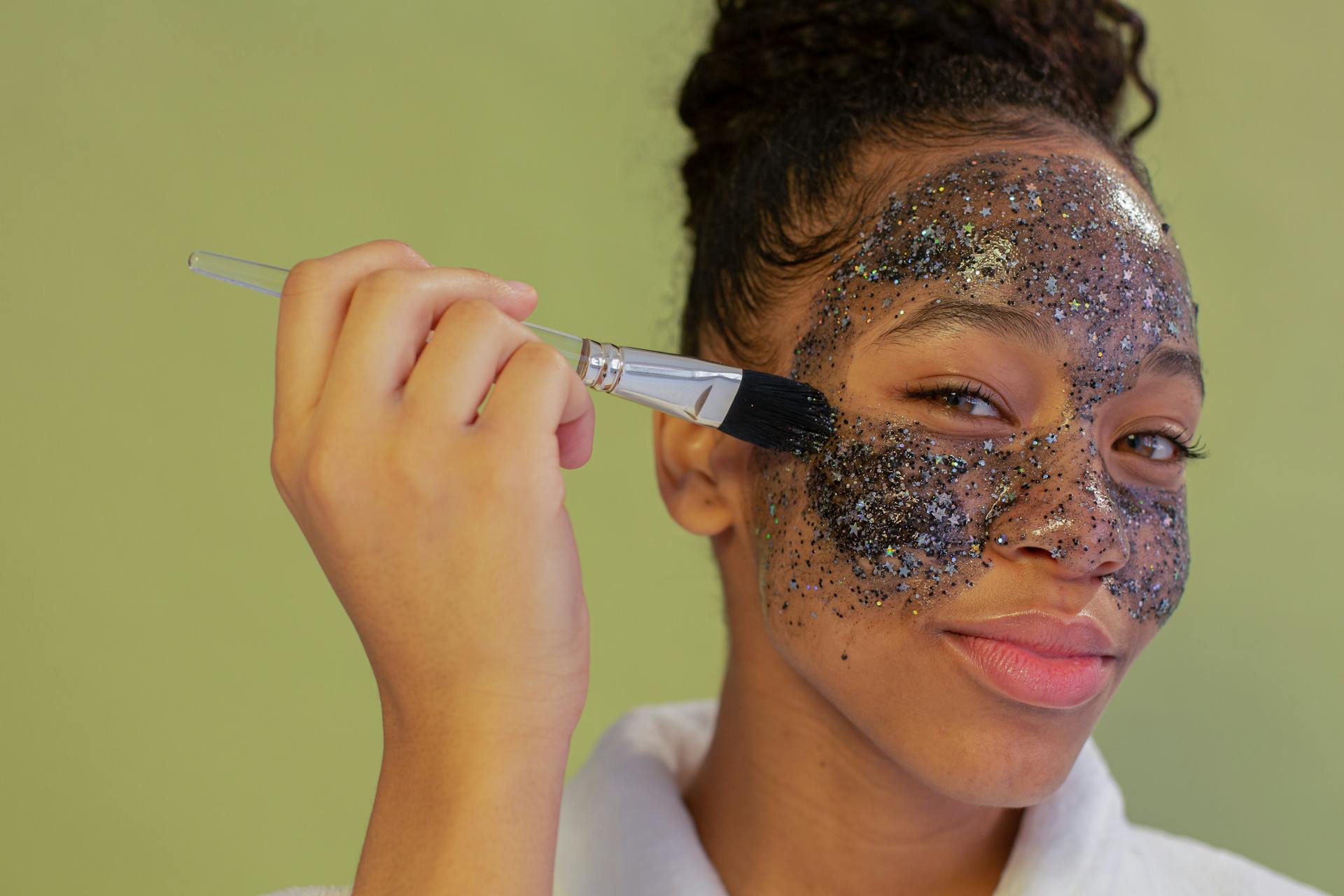 Smiling black woman spreading charcoal mask with brush