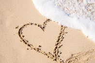 海浪涌来时，沙中画下一颗心，象征爱与自然
