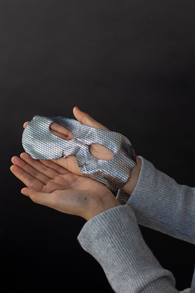 Crop Person Showing Cosmetic Eye Mask On Dark Background