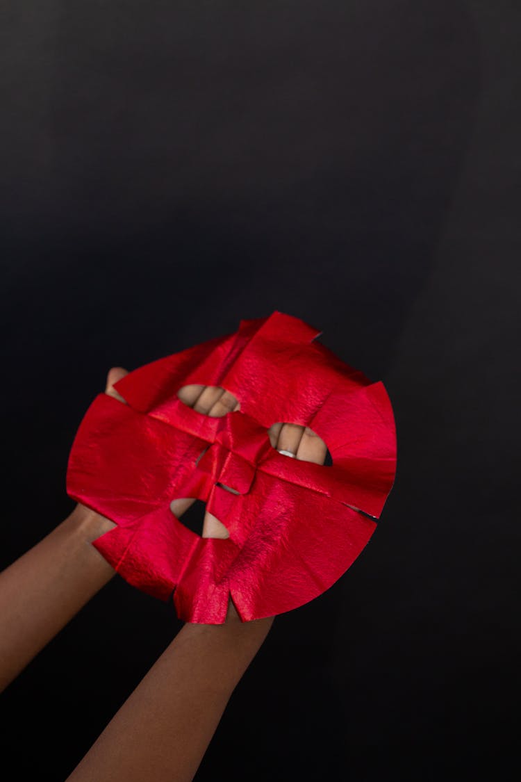 Crop Person Showing Moisturizing Red Mask On Black Background