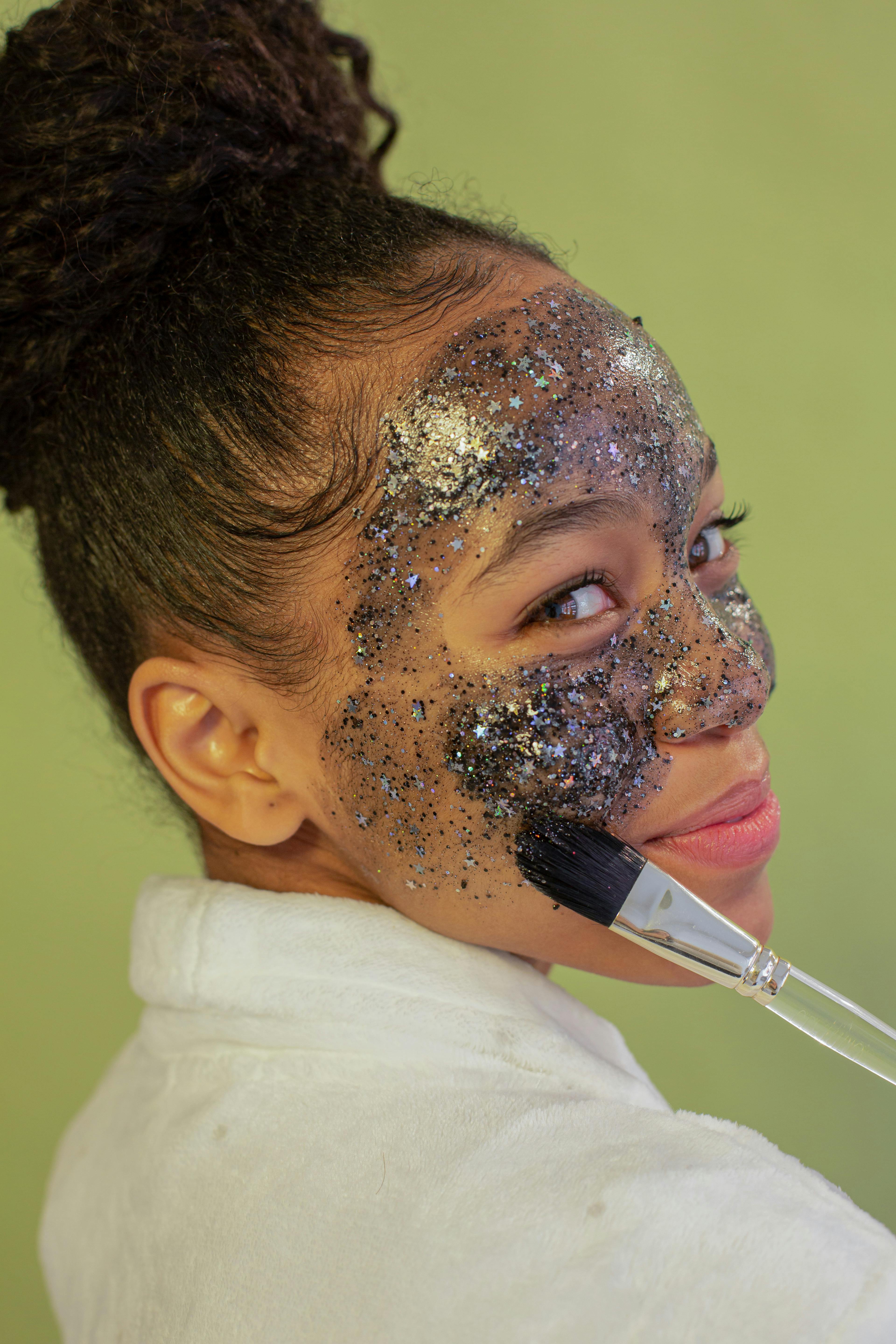 smiling black teen applying peel off mask on face