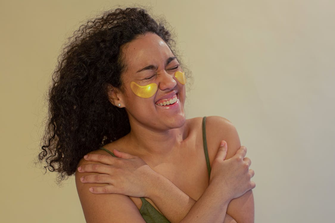 Free Cheerful Young African American Female With Eye Patches And Crossed Arms Laughing With Closed Eyes Stock Photo