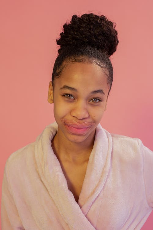 Smiling ethnic teen with lip mask and hair bun