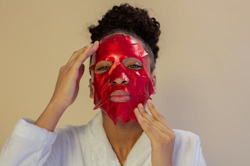 Emotionless black woman applying soothing face mask