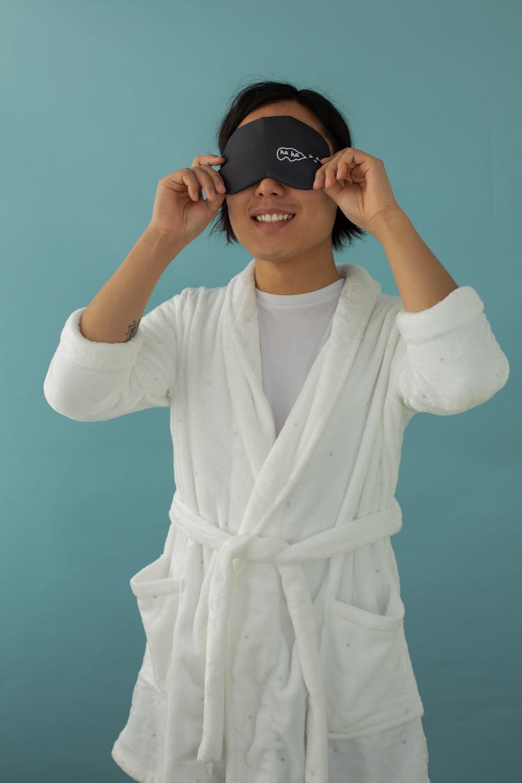 Smiling Asian Man Putting On Sleep Mask On Eyes