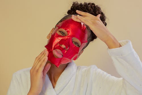 Calm black woman applying cleansing face mask sheet