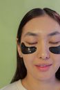 Crop positive Asian woman with eye patches on face