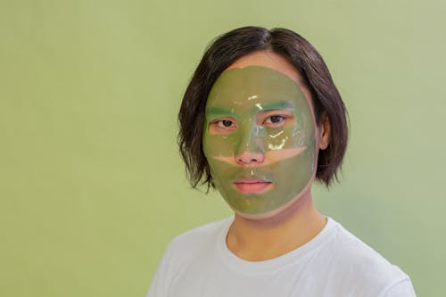 Calm Asian man with facial mask during cosmetic procedure