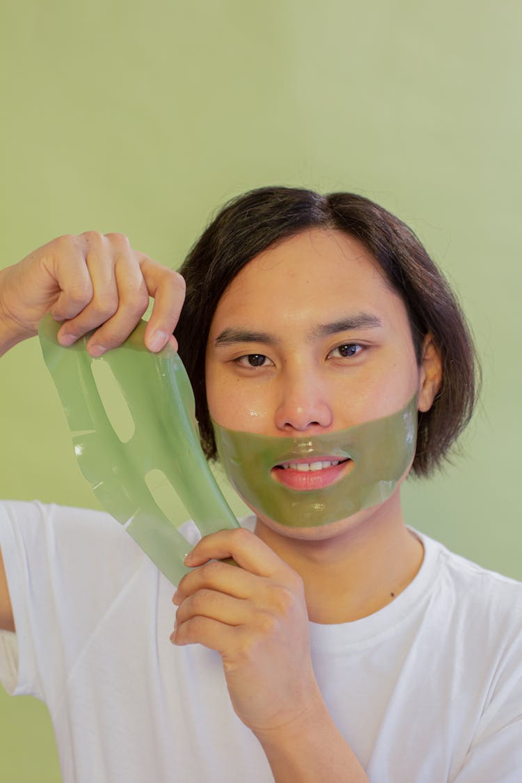 Content Asian Man Applying Green Facial Mask