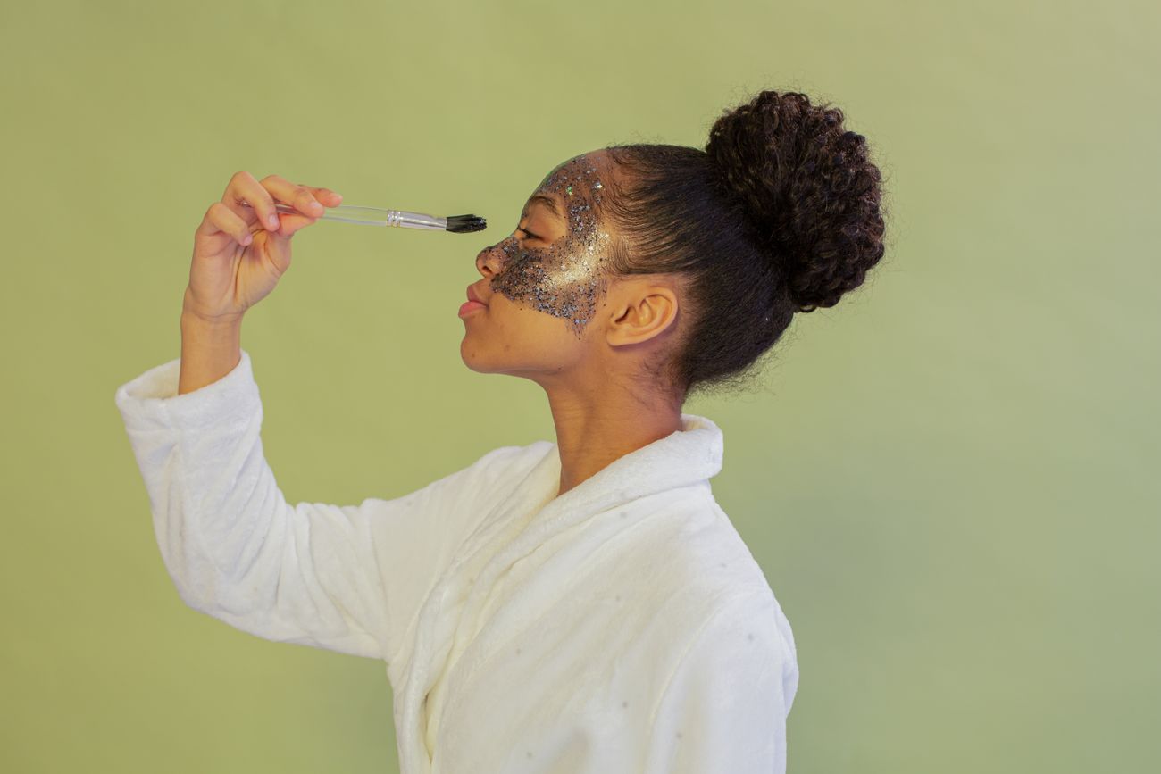 Black woman applying a facial skincare mask