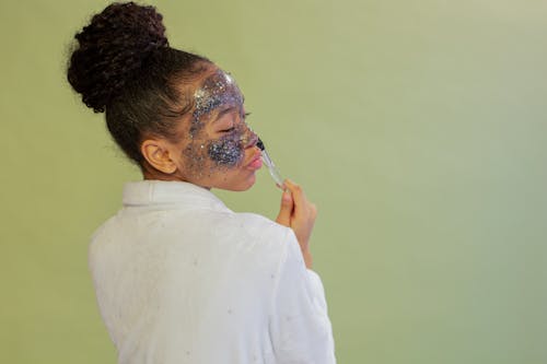 Black woman applying facial mask