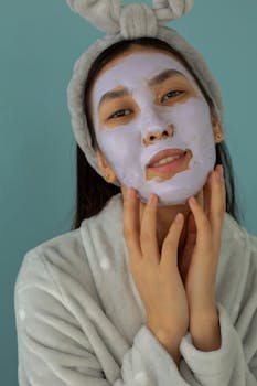 Young woman enjoying a skincare routine with a facial mask indoors.