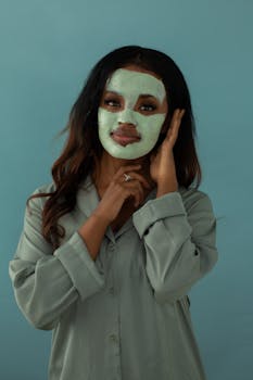 African American woman enjoying skincare routine with green facial mask.