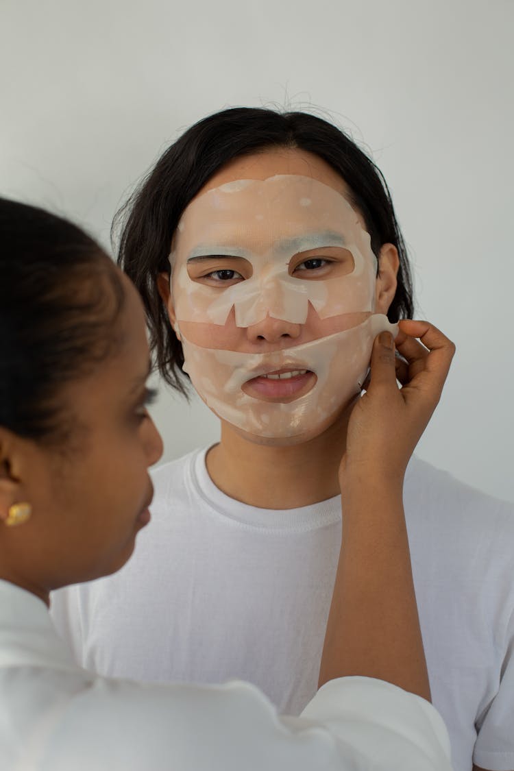 Woman Applying Face Mask On Man 