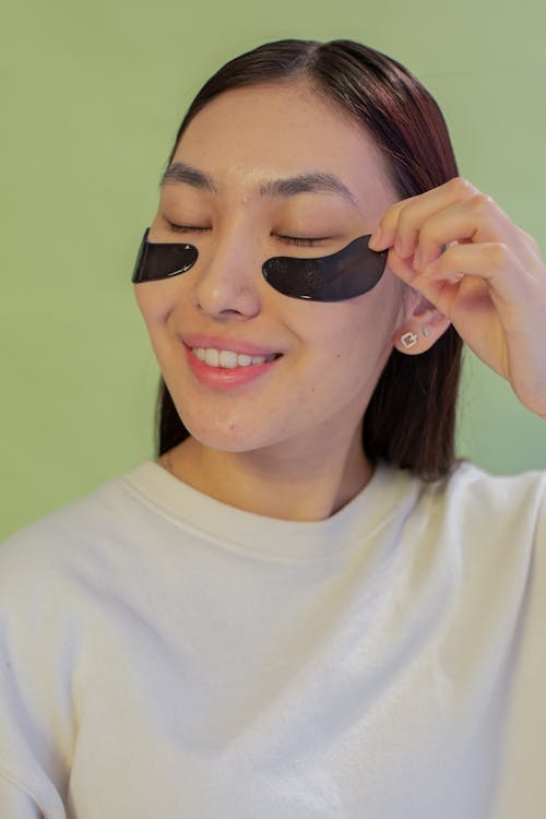 Close Up Photo of a Woman Applying Under Eye Patches