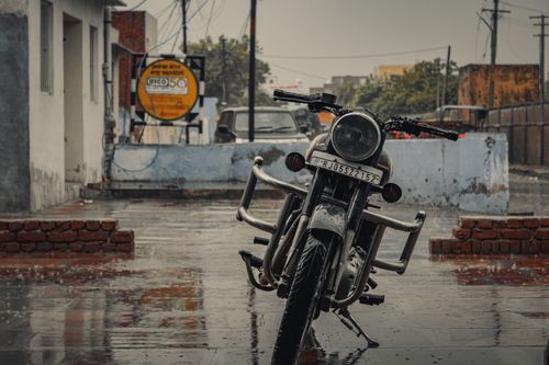 Free A vintage motorcycle parked in a rainy street in Bharatpur, India, showcasing the wet and moody ambiance. Stock Photo