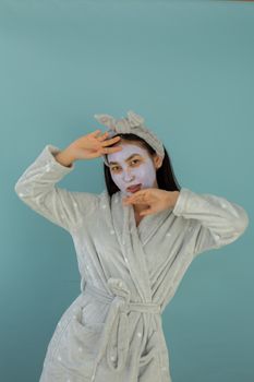 Adult woman wearing a robe and face mask against a blue background, embodying self-care and relaxation.