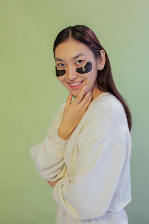 Free A smiling woman wearing under-eye patches in a studio setting, showcasing skincare and beauty routine. Stock Photo