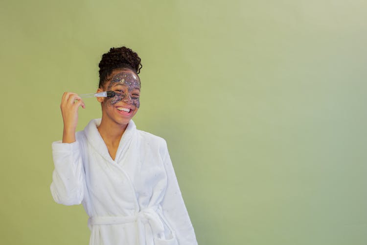 Cheerful Black Teen Applying Scrub Mask On Face