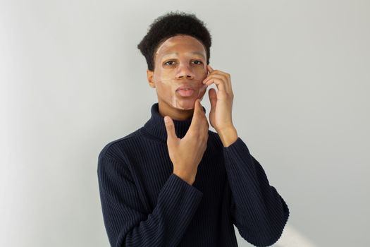 Ethnic man applying sheet mask on face