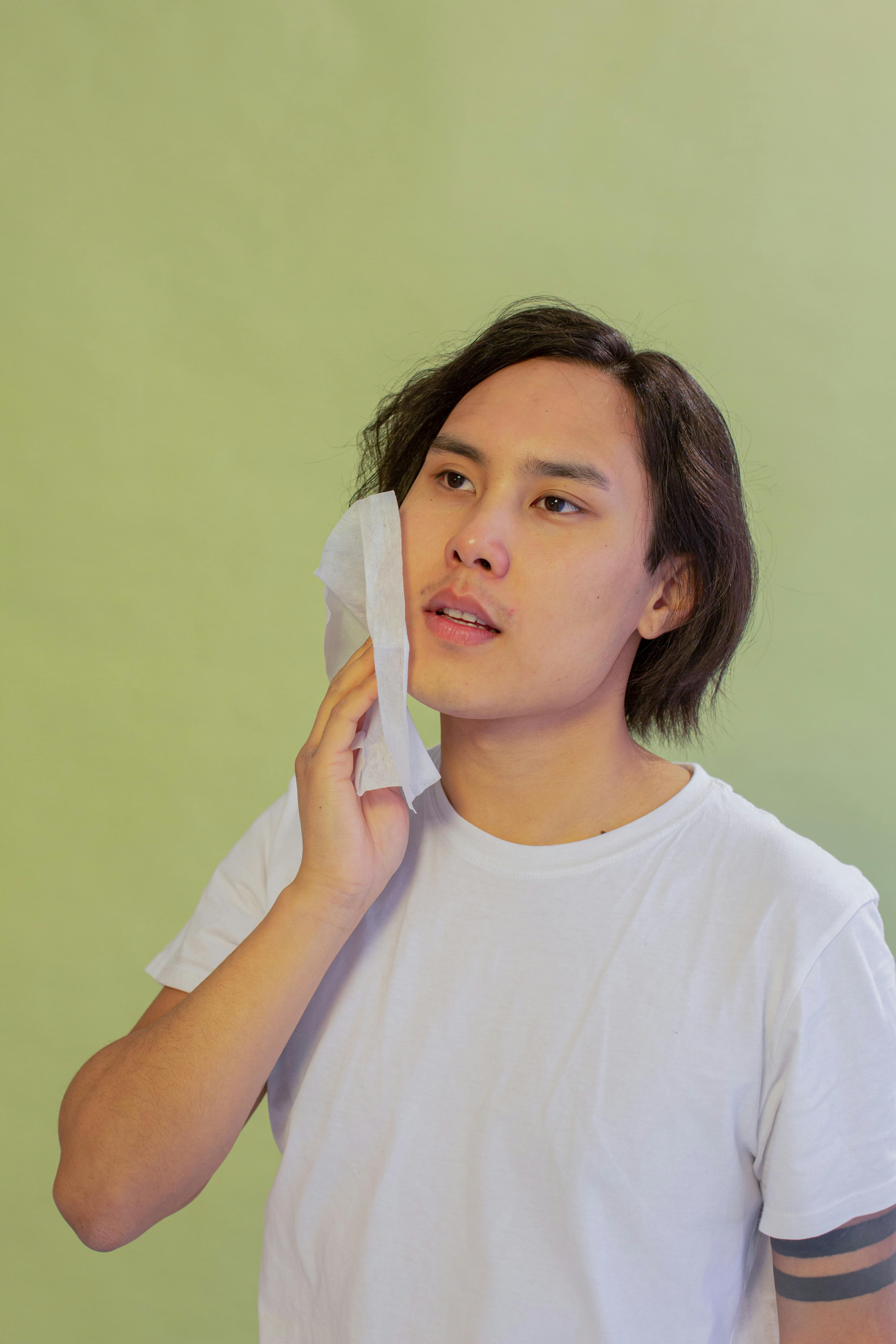 Asian man cleansing cheek with wet wipe · Free Stock Photo