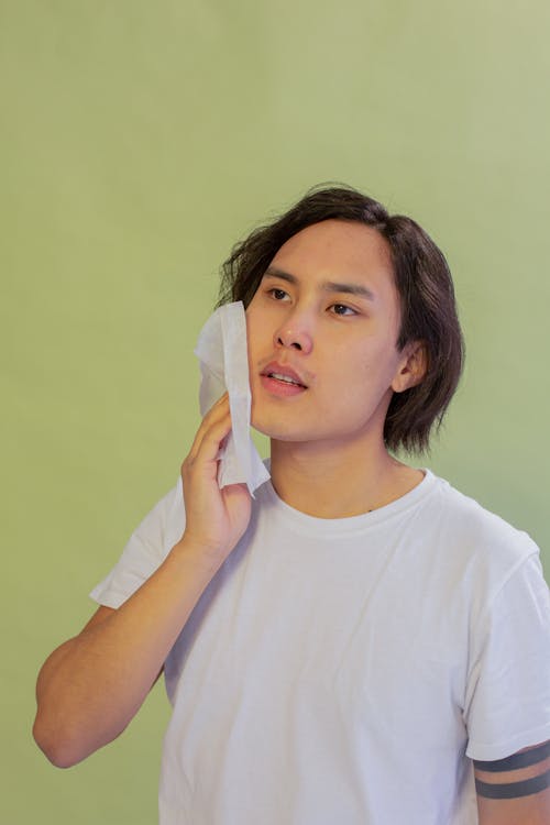 Asian man cleansing cheek with wet wipe