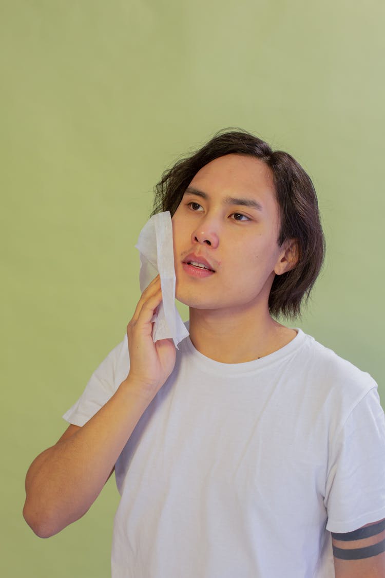 Asian Man Cleansing Cheek With Wet Wipe