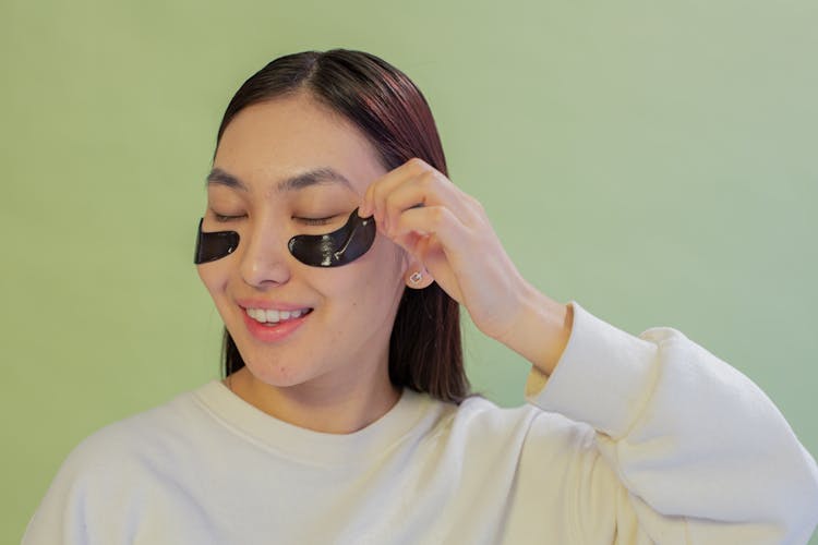 Smiling Asian Teen Removing Eye Patch From Face