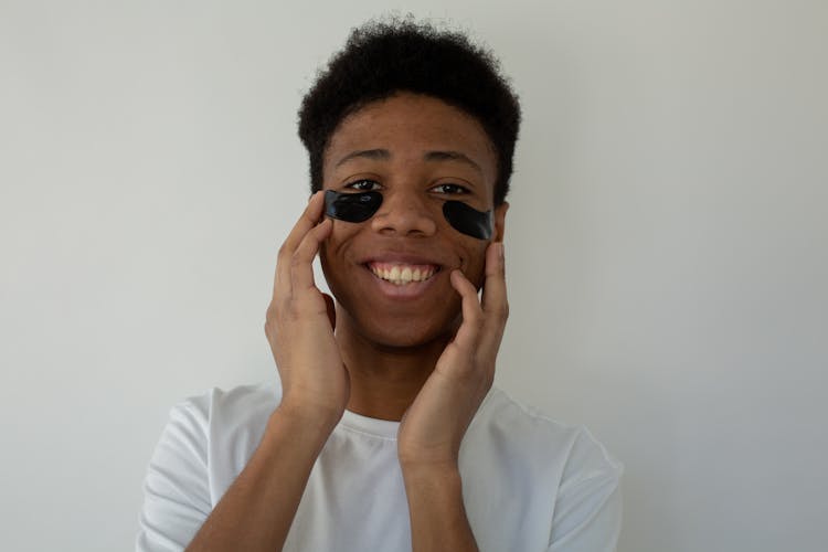 Cheerful Black Teenager Touching Face With Eye Patches