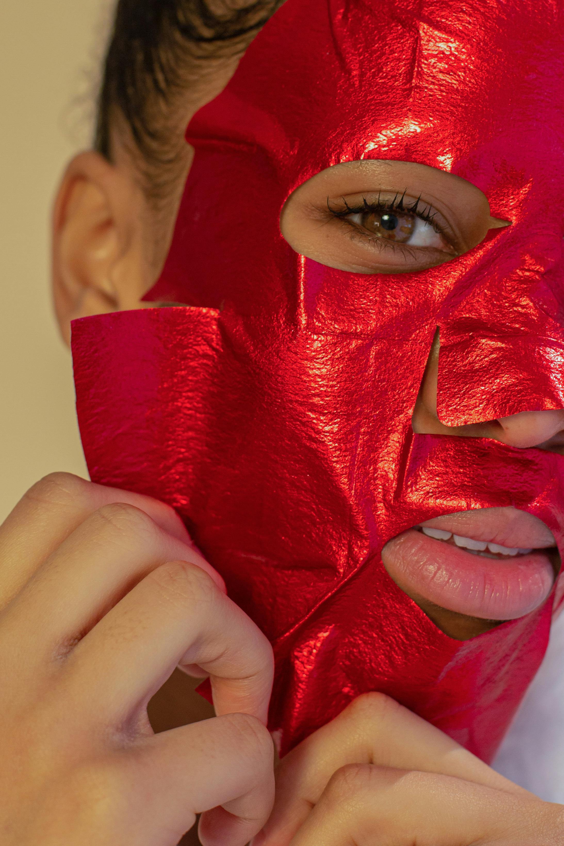 crop ethnic woman removing red sheet mask from face