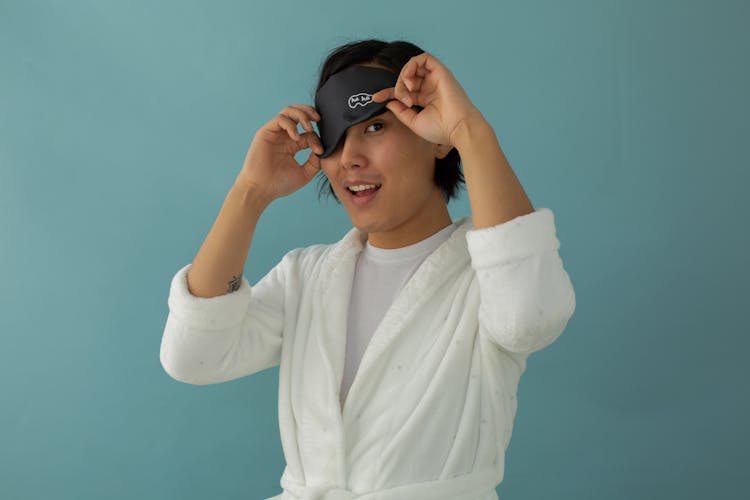 Smiling Asian Man In Eye Mask On Turquoise Background