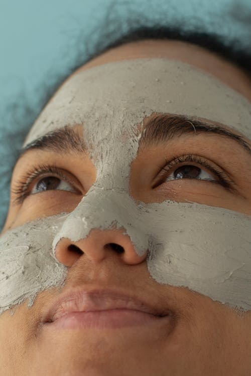 Crop black woman with clay mask on face