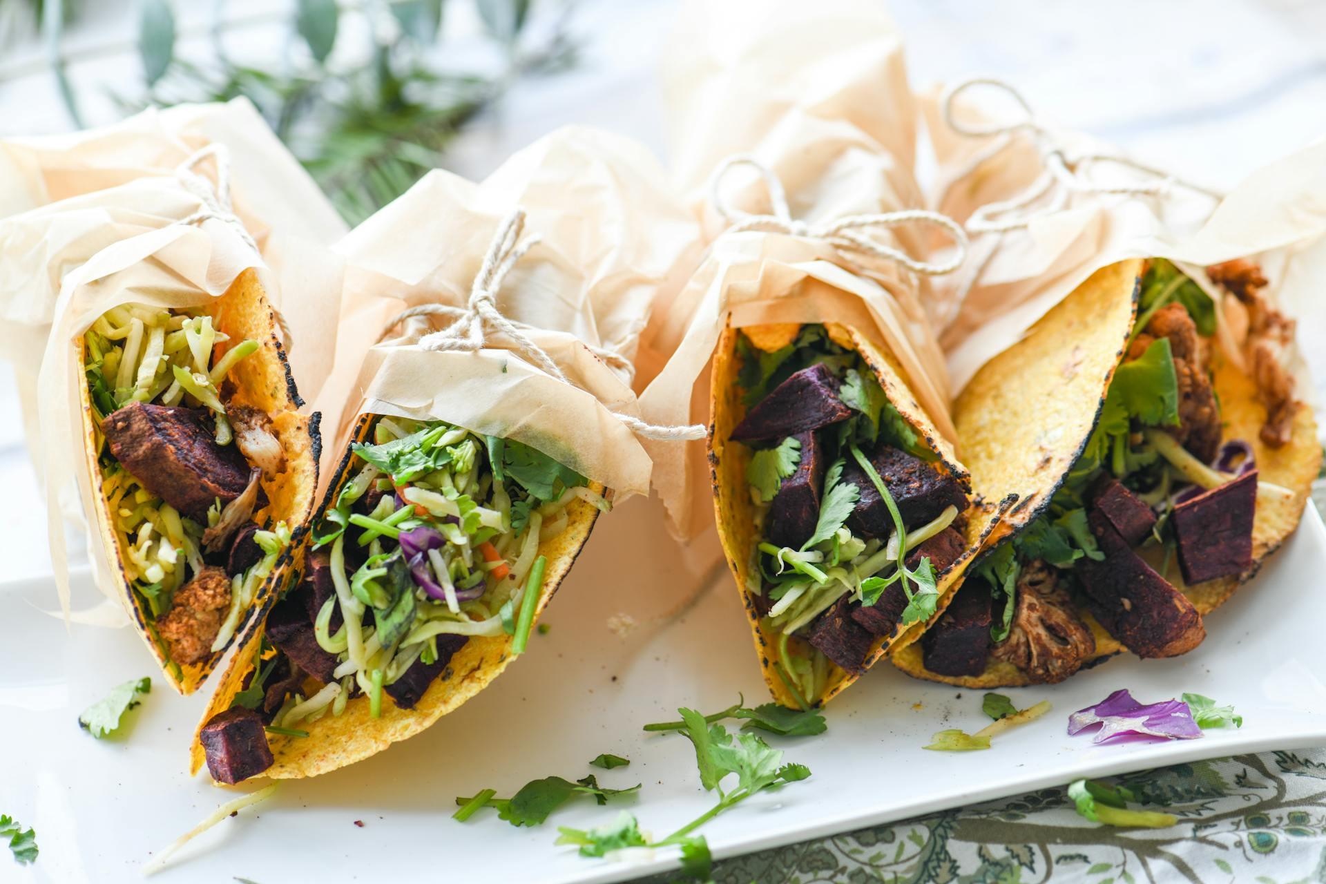 Delicious vegetarian tacos filled with fresh vegetables and herbs wrapped in parchment paper.