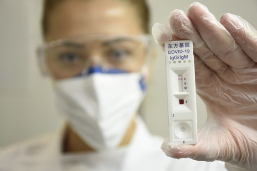 Close-up of a healthcare professional holding a COVID-19 IgG/IgM rapid test kit.