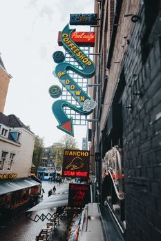 Colorful neon signs on a street in Amsterdam, creating a lively urban atmosphere.