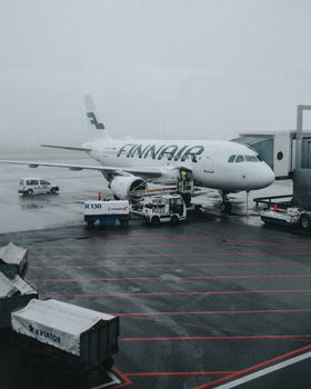 A Finnair airplane parked at the terminal in Amsterdam airport under a gloomy sky.