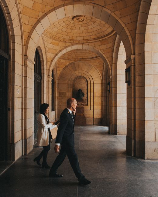 People walking through a grand indoor archway, showcasing elegant architecture.