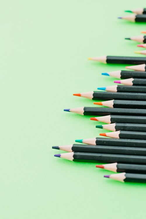 Free A vibrant array of colored pencils neatly arranged on a soft green background, offering artistic inspiration. Stock Photo
