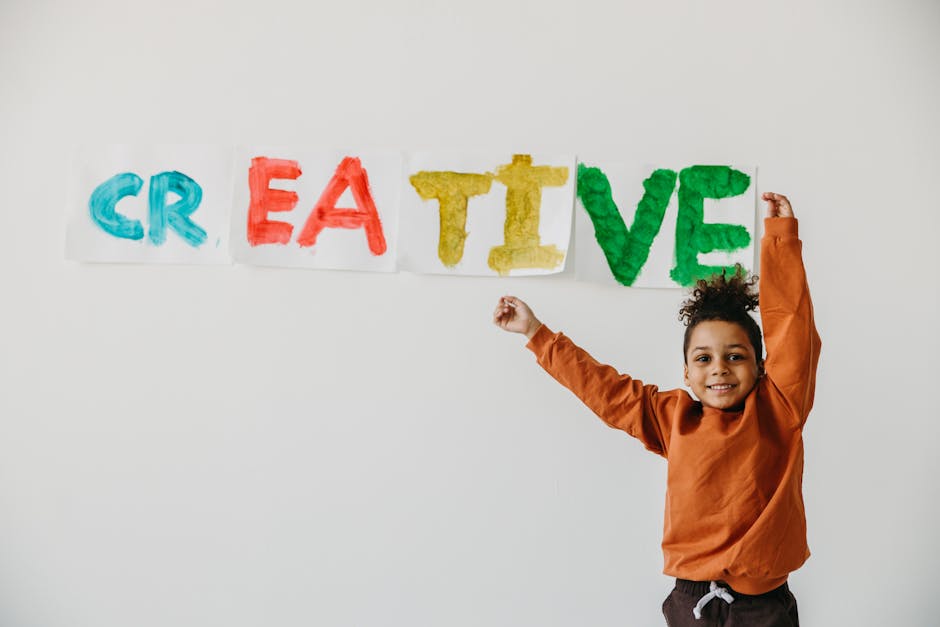 Como Aumentar sua Criatividade com Práticas Diárias 2 Smiling child with arms up in front of colorful 'creative' art on a white wall.