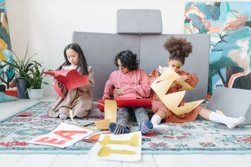 Free Three children creating art with colored paper indoors, showcasing teamwork and creativity. Stock Photo