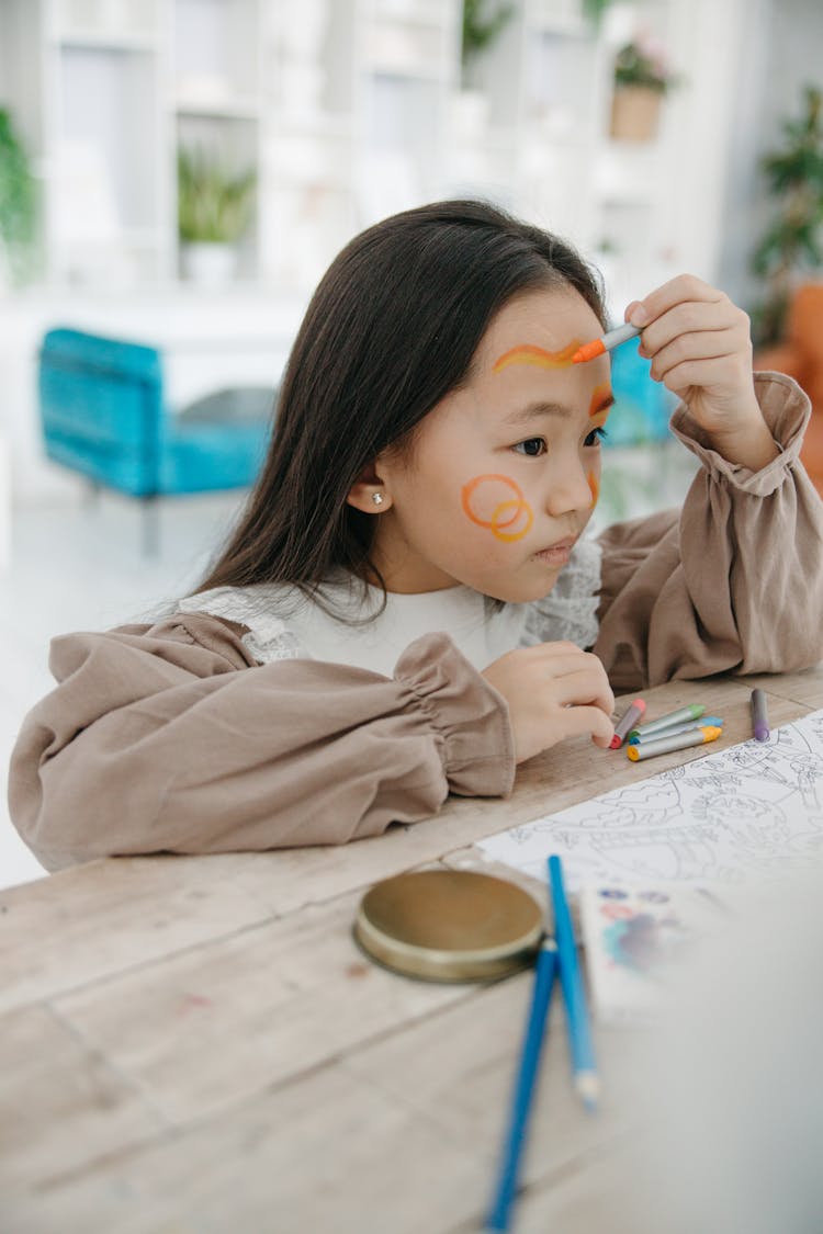 A Girl Drawing  With Crayons On Face