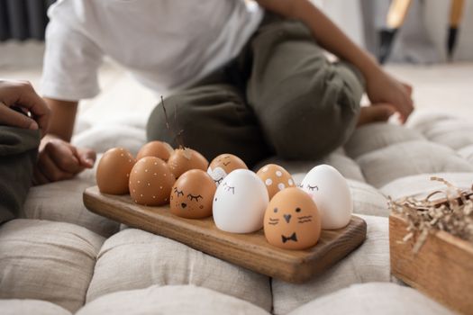 Creative Easter eggs with painted faces and designs on a wooden board, indoor shot.