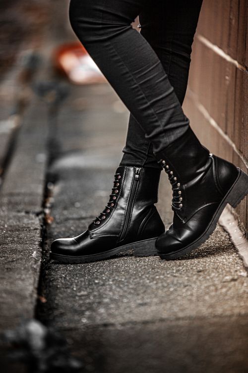 Free Close-up of black leather boots and legs on urban pavement, showcasing fashion in focus. Stock Photo
